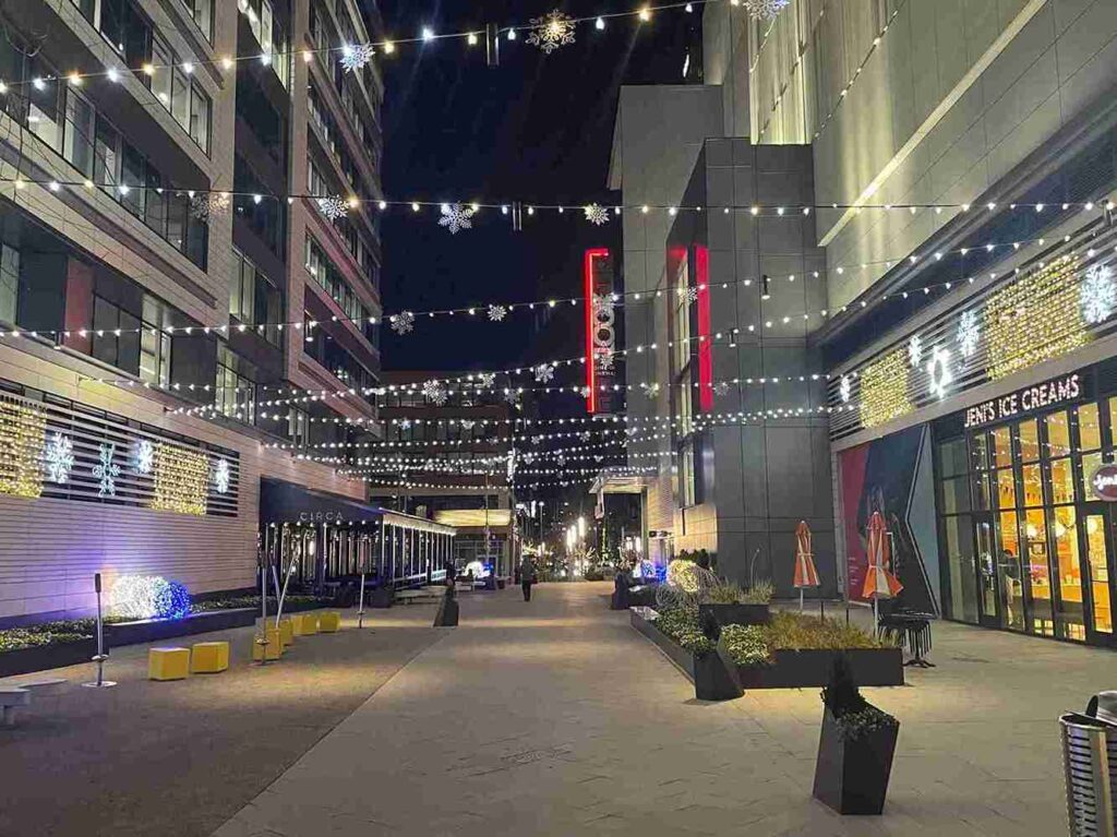 Urban street at night with decorative lights above sidewalk and storefronts, representing vibrant local business district and community in Virginia.